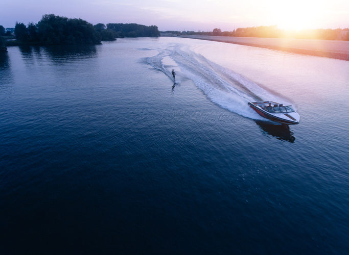 Man water skiiing on lake behind a boat